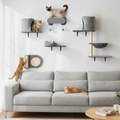 Arbre à chat mural modulaire gris avec plateformes et lits installés au-dessus d'un canapé gris.